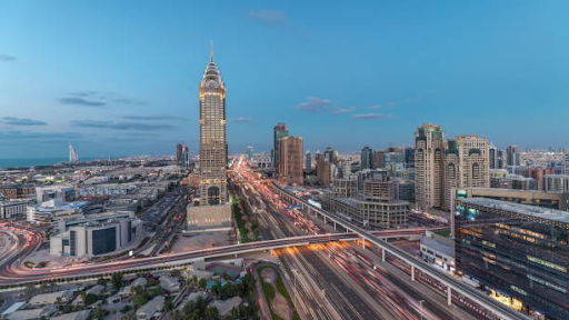 City skyline at dusk with illuminated skyscrapers and busy highways, highlighting luxury investments like ELO 3.